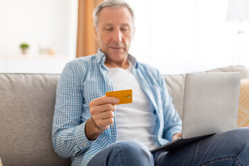 Wall Mural - Smiling mature man using pc and credit card at home