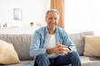 © Prostock-studio - Smiling mature man sitting on the couch and posing