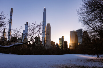 Wall Mural - Winter Landscape and Midtown Manhattan Skyline along the Snow Covered Sheep Meadow at Central Park in New York City during a Sunset