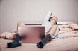 a young Asian webcam model girl is lying in front of a laptop with her legs spread. enjoys and shows her charms. low depth of focus,selective focus.
