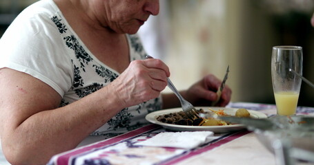 Senior woman eating lunch, casual older person at kitchen eating meal