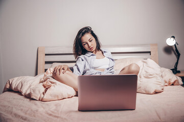 Wall Mural - a young Asian webcam model girl is sitting in front of a laptop with her legs spread. she communicates and shows her charms. low depth of focus,artistic photo processing