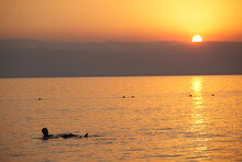 Man Floating In The Dead Sea At Sunset, Jordan