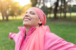 © PintoArt - happy mature woman smiling with a pink scarf, symbol against breast cancer, - positive cancer fighter concept -