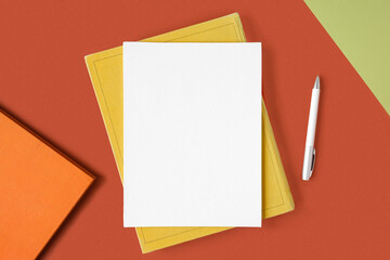 Blank canvas sheet with pen on red orange background, office supplies on table. Top view, flat lay, copy space. Net white page. Card mockup. Elegant layout, template. Soft shadow. Minimal design