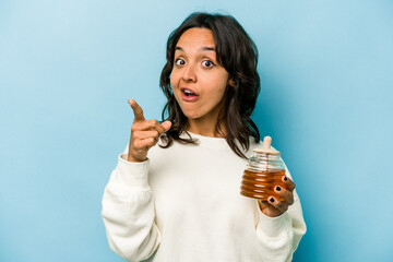 Wall Mural - Young hispanic woman holding a honey isolated on blue background having an idea, inspiration concept.