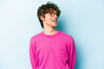 Wall Mural - Young caucasian man isolated on blue background relaxed and happy laughing, neck stretched showing teeth.