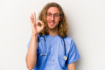 Young nurse caucasian man isolated on blue background cheerful and confident showing ok gesture.