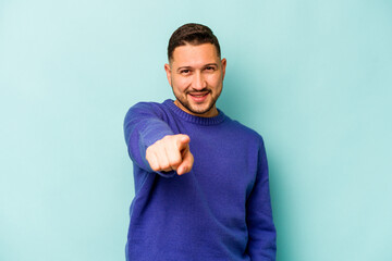 Wall Mural - Young hispanic man isolated on blue background cheerful smiles pointing to front.