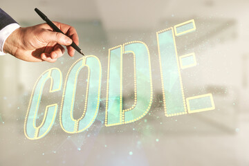 Poster - Man hand with pen writes Code word hologram on blurred office background, artificial intelligence and neural networks concept. Multiexposure