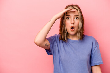 Wall Mural - Young caucasian woman isolated on pink background looking far away keeping hand on forehead.