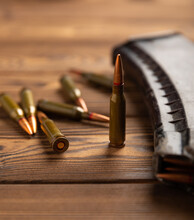 Bullets And Ammo Magazine With Kalashnikov Assault Rifle On Brown Wood. Composition With Place For Text. Cartridges For A Rifle And A Carbine On A Wooden Background. Military Concept.
