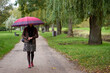 Young stylish woman walking in the autumn park with huge red umbrella.