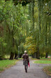 Young short haired blonde woman walks in the autumn park with red umbrella. View from back.