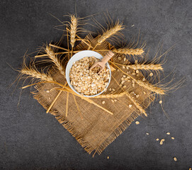 Wall Mural - Oat flakes in a white bowl and wheat ears. Beautiful kitchen table.