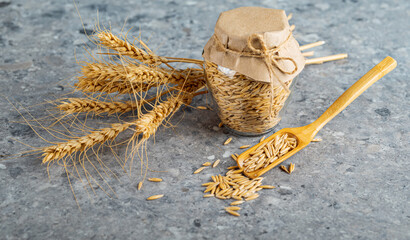 Wall Mural - Wheat grains in a glass jar and wheat ears on the kitchen table. Close-up