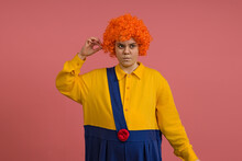 A Girl In A Clown Costume And A Bright Wig Pursed Her Lips, Studio Portrait On A Colored Background