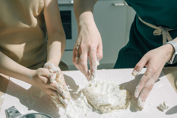 Mother Helping Daughter daughter kneading dough in Kitchen to Bake Cookies. Mom and daughter bake pizza in the kitchen together