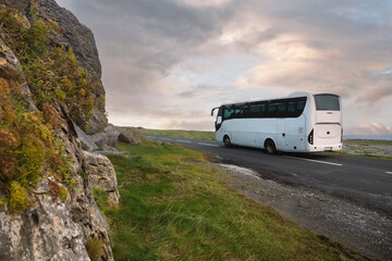 white bus passing mountain. beautiful cloudy sky in the background. tourism industry. west of irelan