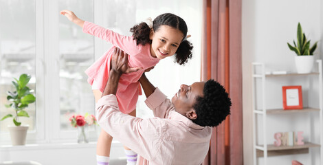 Poster - Happy African-American man playing with his little daughter at home