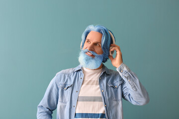 Poster - Portrait of senior man with unusual color of hair and beard listening to music on blue background