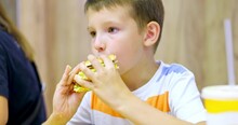 Cute Boy Eating Large Hamburger At Fast Food Restaurant. Unhealthy Meal For K