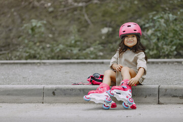 Cute little girl in a spring park with rollers