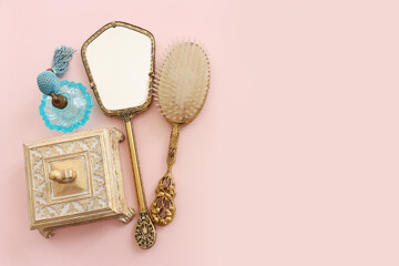 Wall Mural - Image of vintage hair comb, perfume bottle and hand mirror over pastel pink background