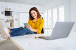 © contrastwerkstatt - Laughing young woman sitting at her desk in office. Feet on the table and looks at her cell phone