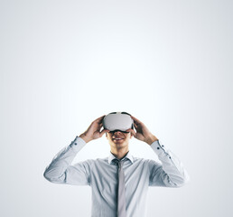Aufkleber - Virtual reality concept with young businessman gets new emotions in VR glasses on abstract light grey background and empty space on his head for you text, mock up