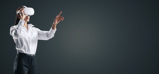 Aufkleber - Young businesswoman working in virtual reality environment in VR glasses, presses by her finger on virtual interface on abstract black backdrop. Innovate and future technology concept, mock up
