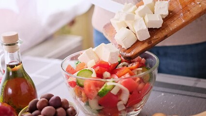 Wall Mural - greek salad preparation series concept - woman pouring sliced feta cheese into a bowl