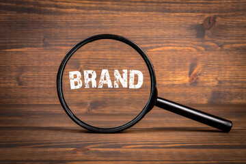 Wall Mural - brand. business concept. black magnifying glass on a wooden background