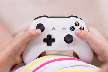 Closeup little girl hands with joystick play video game.