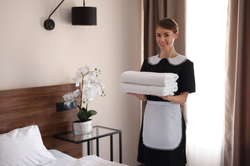 Sticker - Beautiful chambermaid with stack of fresh towels in hotel room