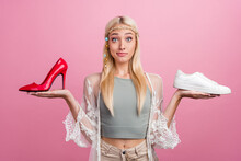 Portrait Of Attractive Skeptic Minded Girl Holding On Palms Choosing Shoes Isolated Over Pink Pastel Color Background