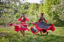 Two Dancers In Traditional Gypsy Dresses Dance In Nature On A Spring Day