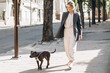 © anatoliycherkas - Mature blond business woman in a gray jacket smiling walking her dog breed amstaff and talking on the phone