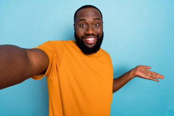 Canvas Print - Photo of pretty cute guy dressed orange t-shirt tacking selfie holding arm empty space isolated blue color background