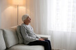 © Evrymmnt - Portrait of elderly lady alone at home. Senior woman 86 years of age sitting on the couch by the window in her apartment. Background, copy space, close up.
