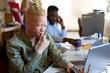 © Wavebreak Media - African american mid adult albino businessman working on laptop at desk in office