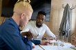 © Wavebreak Media - African american mid adult businessman with albino male colleague discussing at desk in office