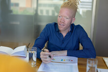 African American Mid Adult Albino Businessman Looking Away While Working On Graphs At Desk In Office
