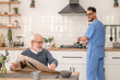 Cheerful caretaker preparing breakfast for an aged man