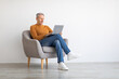 © Prostock-studio - Confident mature man using laptop sitting on chair