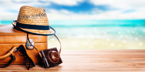 vintage suitcase, sunglasses and hipster hat wooden deck and blur tropic sea background. summer para