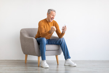 Poster - Mature man using cell phone celebrating success shaking fists