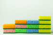 stack of porous multicolored sponge scourers on grey background.