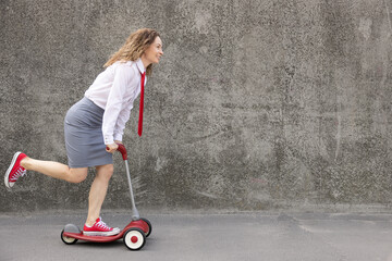 Wall Mural - Funny businesswoman riding scooter outdoor