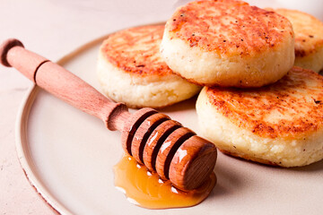 Wall Mural - Cottage cheese pancakes, with honey, close-up, on a beige table, selective focus, no people,